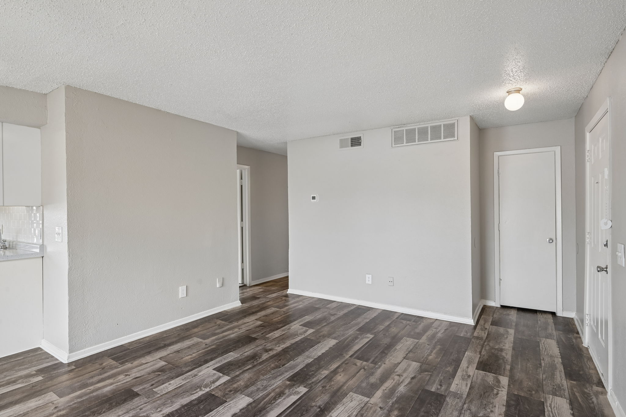 A room with wooden flooring and white walls.
